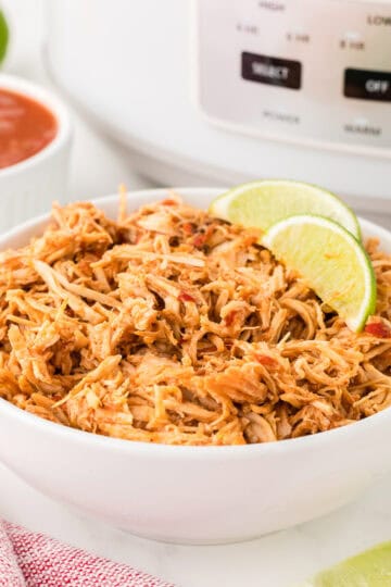 slow cooker salsa chicken in a bowl in front of a crock pot